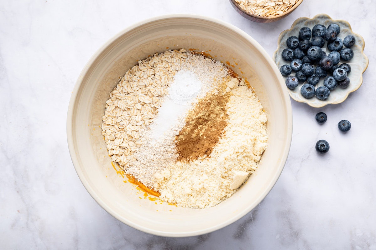 The dry ingredients added to the wet ingredients for the sweet potato blueberry oatmeal cookies (rolled oats, oat flour, baking soda, cinnamon, almond flour and salt).