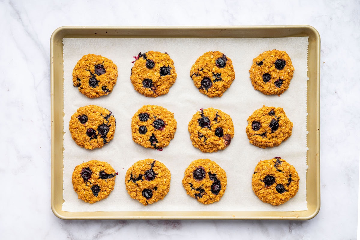 12 sweet potato blueberry oatmeal cookies on a baking sheet lined with parchment paper.