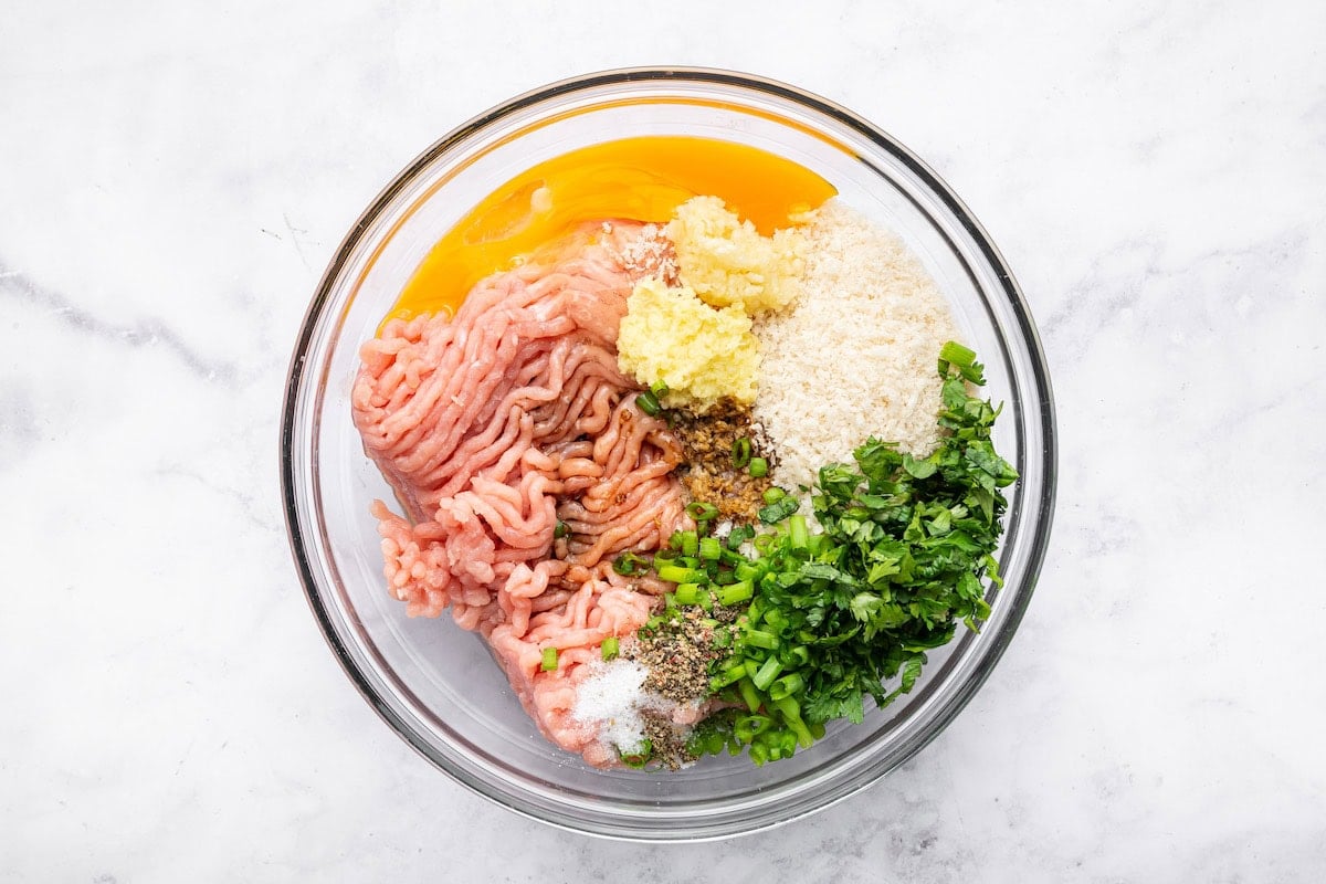 The Thai chicken meatball ingredients in a glass mixing bowl before being combined.