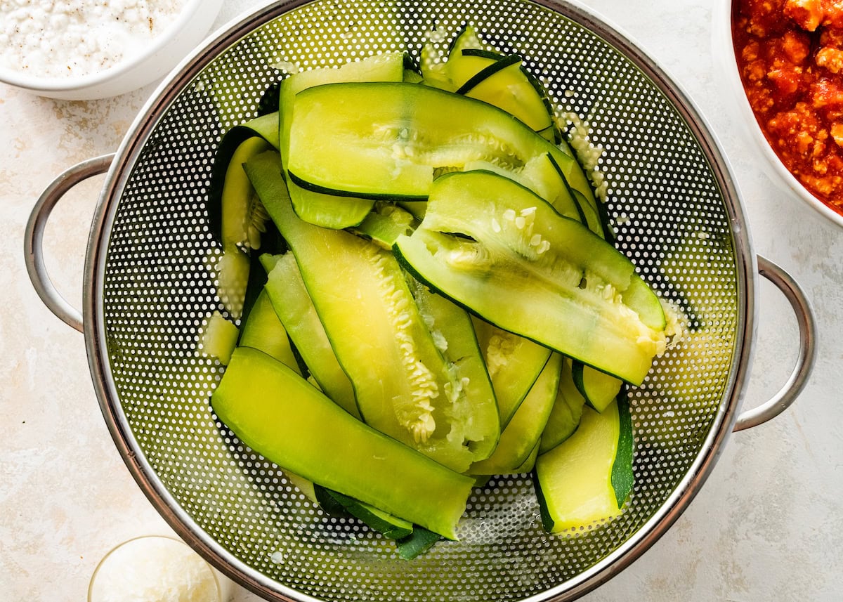 Boiled zucchini slices in a metal strainer.