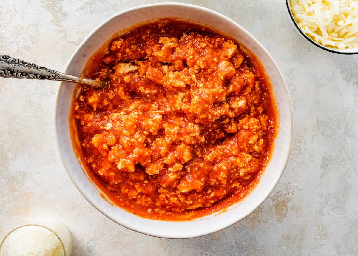 Crumbled tofu in a small bowl with marinara sauce.
