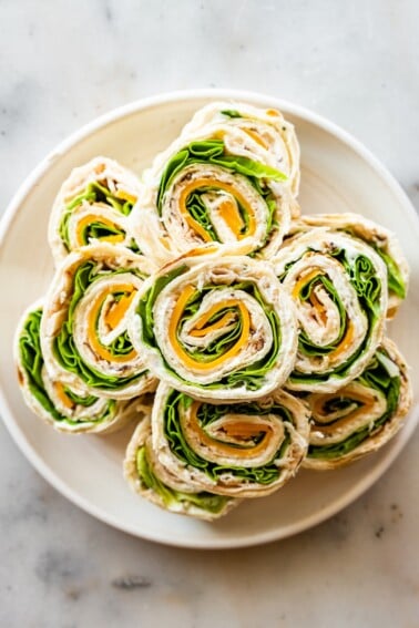 Multiple turkey pinwheel sandwiches on a plate.